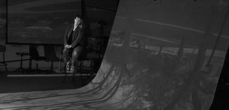 Deej Gausling, digital photography instructor, sits inside her working classroom-sized camera. Like a real camera, the image is projected upside-down onto the “sensor.”