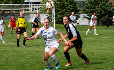 Two female athletes playing soccer.