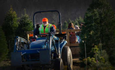 Tractor driver waves at photographer while taking people for a ride.