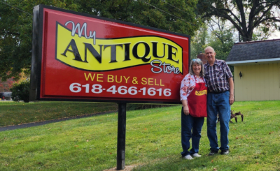 Owners stand beside my antique store sign